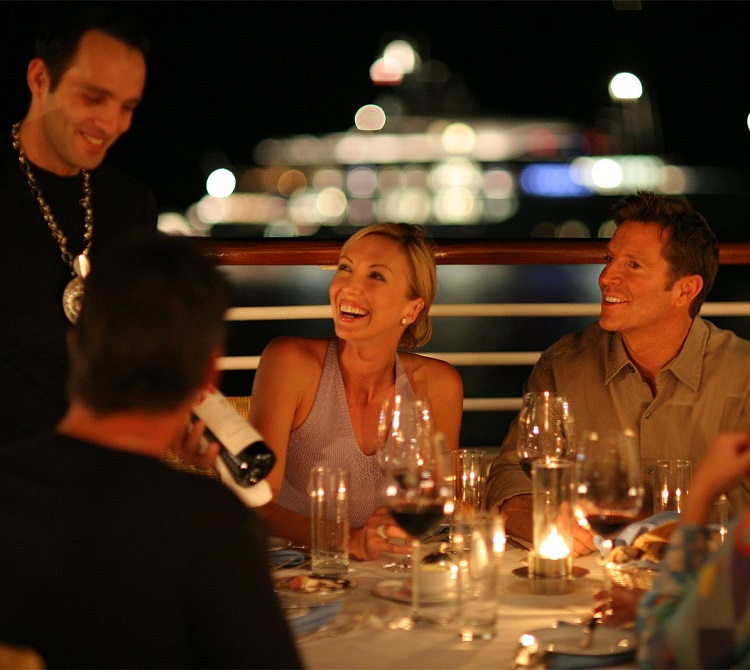 Woman smiling as group dine on-board a luxury cruise