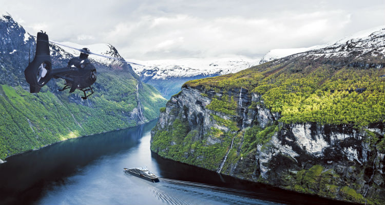 Scenic Eclipse sailing and helicopter passing between Norwegian Fjords