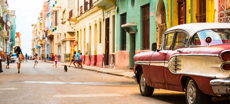 Pink and white classic car parked on a bright Cuban street