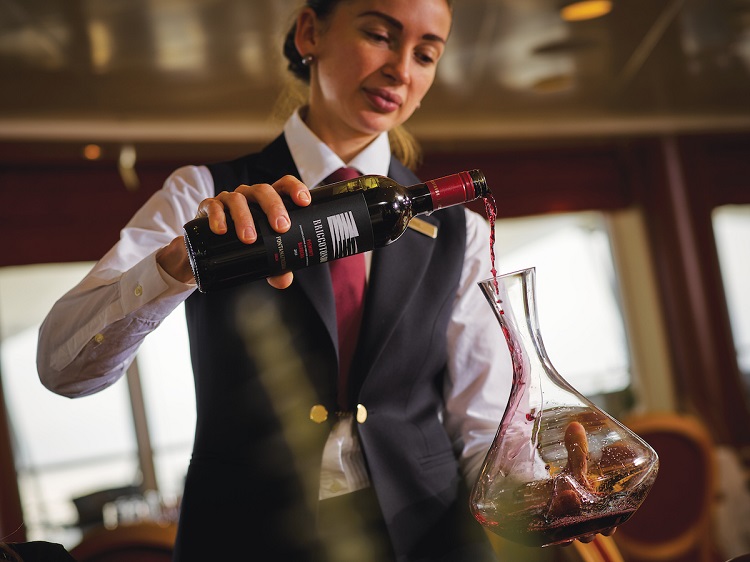 A sommelier pouring red wine into a decanter on-board a Silversea cruise ship