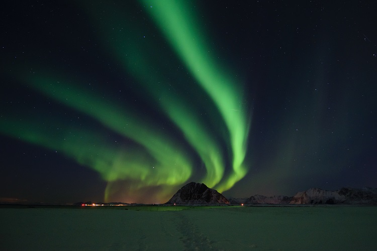 The Northern Lights in streams over the snow and mountains in Lofoten in Norway