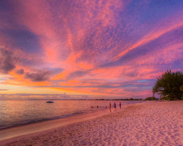 Seven Mile Beach in Grand Cayman bathed in pink light at sunset