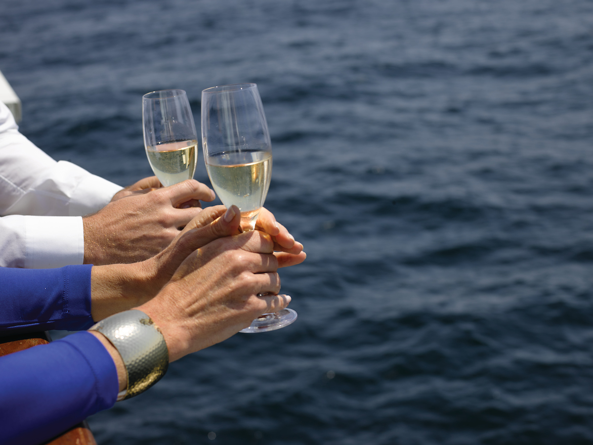 Silversea passengers holding glasses of wine as they look out over the side of their cruise ship