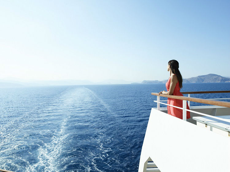 Woman looking out to the horizon on a Seabourn ship balcony